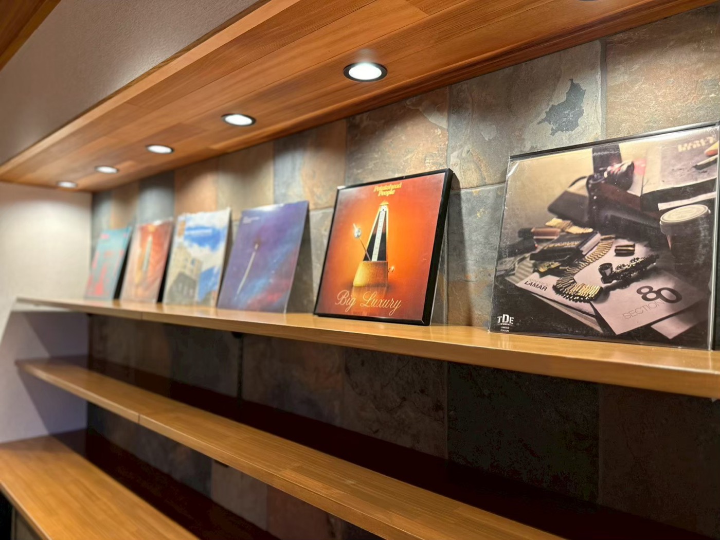 レコード棚クローズアップ。石タイル壁と木板天井の趣味コーナー